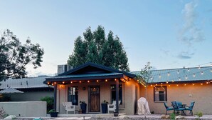 Una casa con porche, mobiliario exterior e iluminación con luces colgantes.