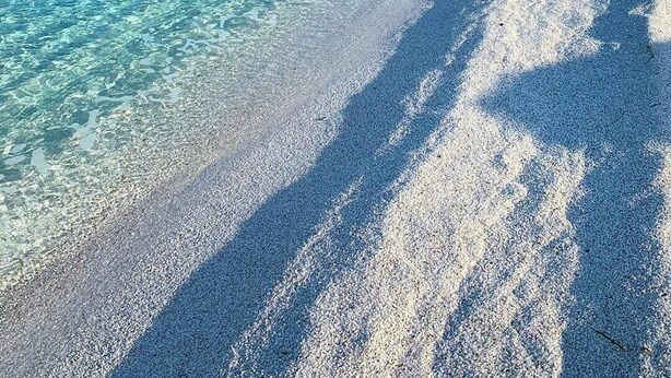 A beach with clear turquoise water, a pebbly shore, and rocky cliffs in the background. - Spacious Holiday Home 10 Minutes from the Stunning Beaches of Western Sardinia (Donigala Fenughedu)