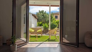 A room with a sliding glass door leading to a patio with outdoor furniture and a view of a building and trees. - Spacious Holiday Home 10 Minutes from the Stunning Beaches of Western Sardinia (Donigala Fenughedu)