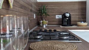 A modern kitchen with a gas stove, a coffee maker, and a decorative placemat with "VIP Lounge" text. - Spacious Holiday Home 10 Minutes from the Stunning Beaches of Western Sardinia (Donigala Fenughedu)
