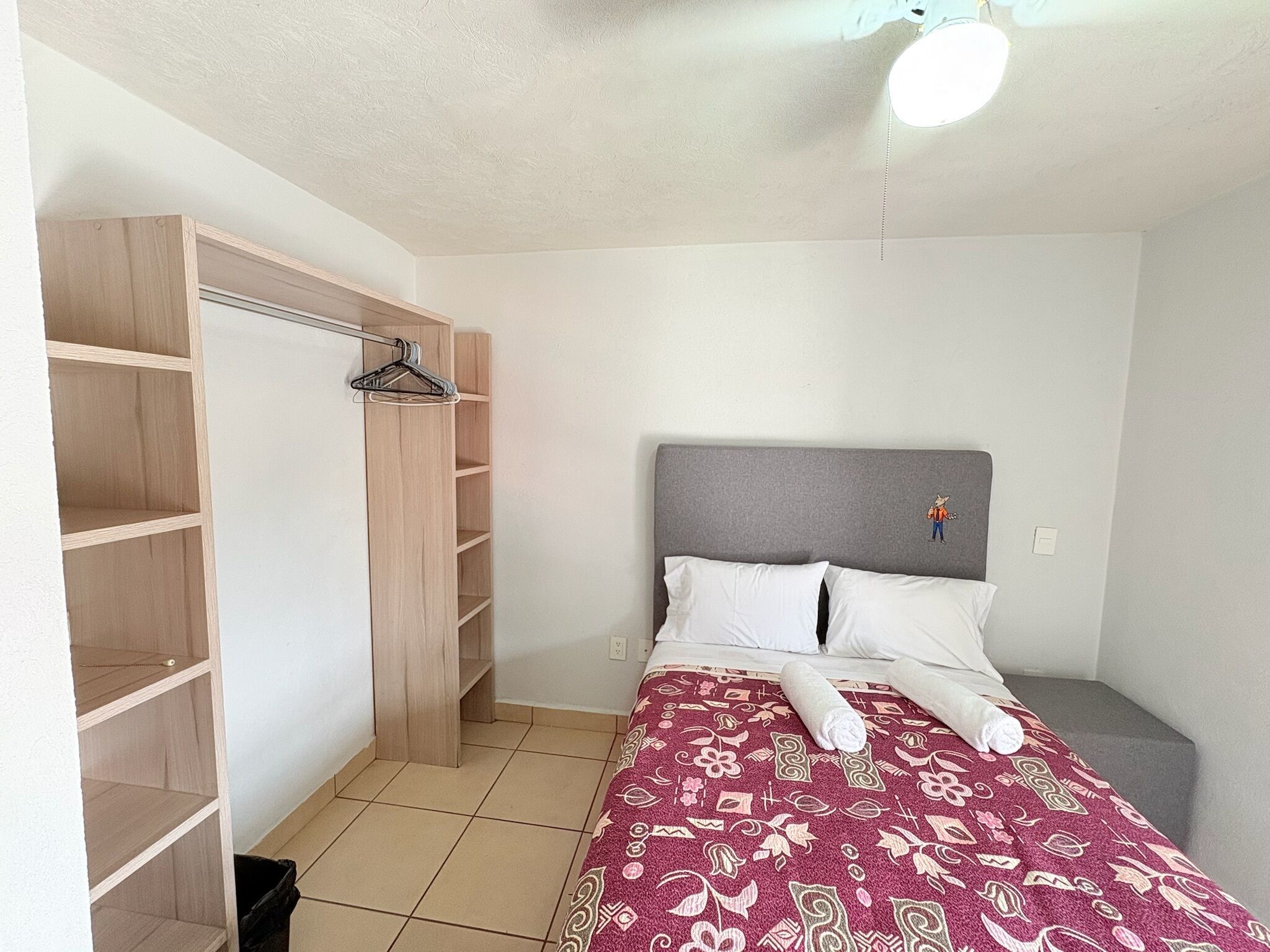 A bedroom with a bed, a wardrobe, and a ceiling fan.