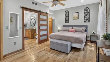 A bedroom with a bed, a ceiling fan, a sliding door, and a bathroom visible through an open door.