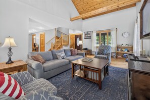 A living room with a sofa, armchair, and coffee table, a staircase, and a bookshelf. - Story Time Retreat (Nashville)