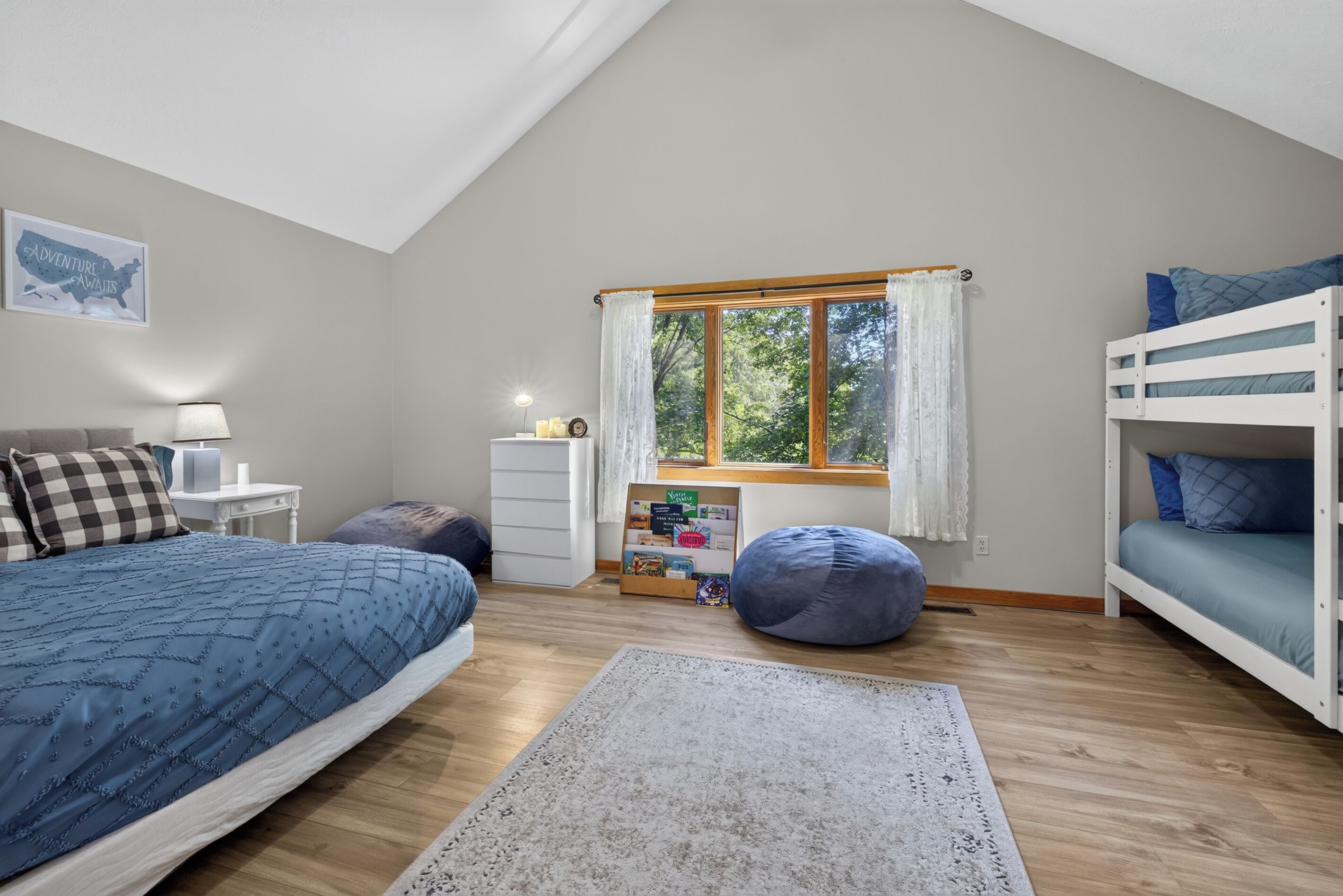 Une chambre avec un lit superposé, un bureau, une chaise, un tapis et une fenêtre avec des rideaux.