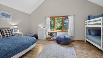Une chambre avec un lit superposé, un bureau, une chaise, un tapis et une fenêtre avec des rideaux.
