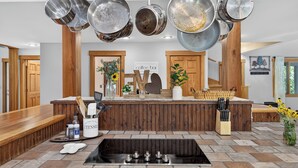 Une cuisine dotée d’un îlot central, d’une cuisinière encastrée et de casseroles suspendues.