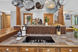 A kitchen with a central island, a built-in stove, and hanging pots. - Story Time Retreat (Nashville)