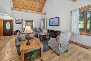 A spacious living room with a high ceiling, a fireplace, a television, and a comfortable seating area. - Story Time Retreat (Nashville)