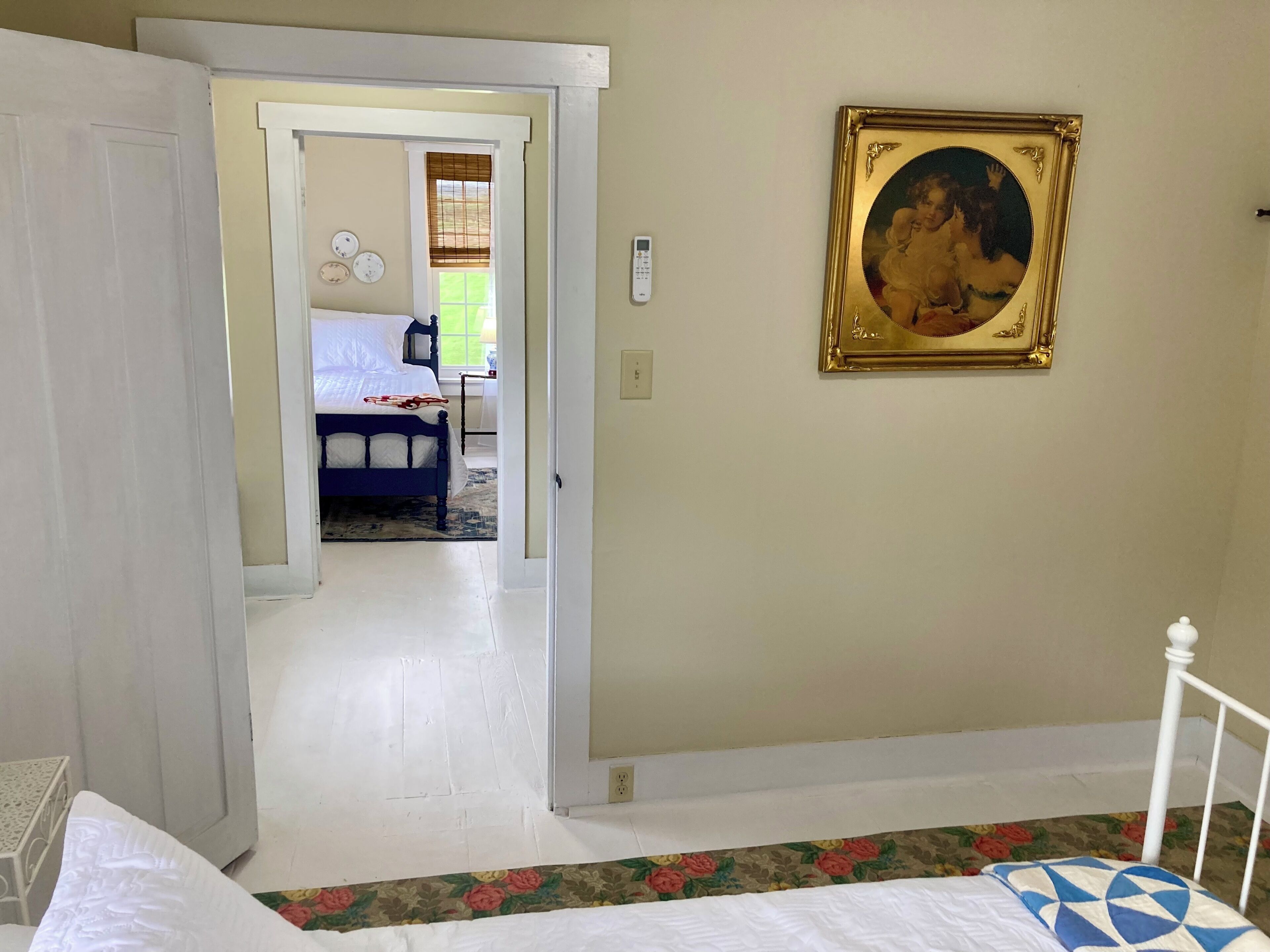 Une chambre à coucher avec un lit, un tableau et une porte donnant sur une autre pièce.