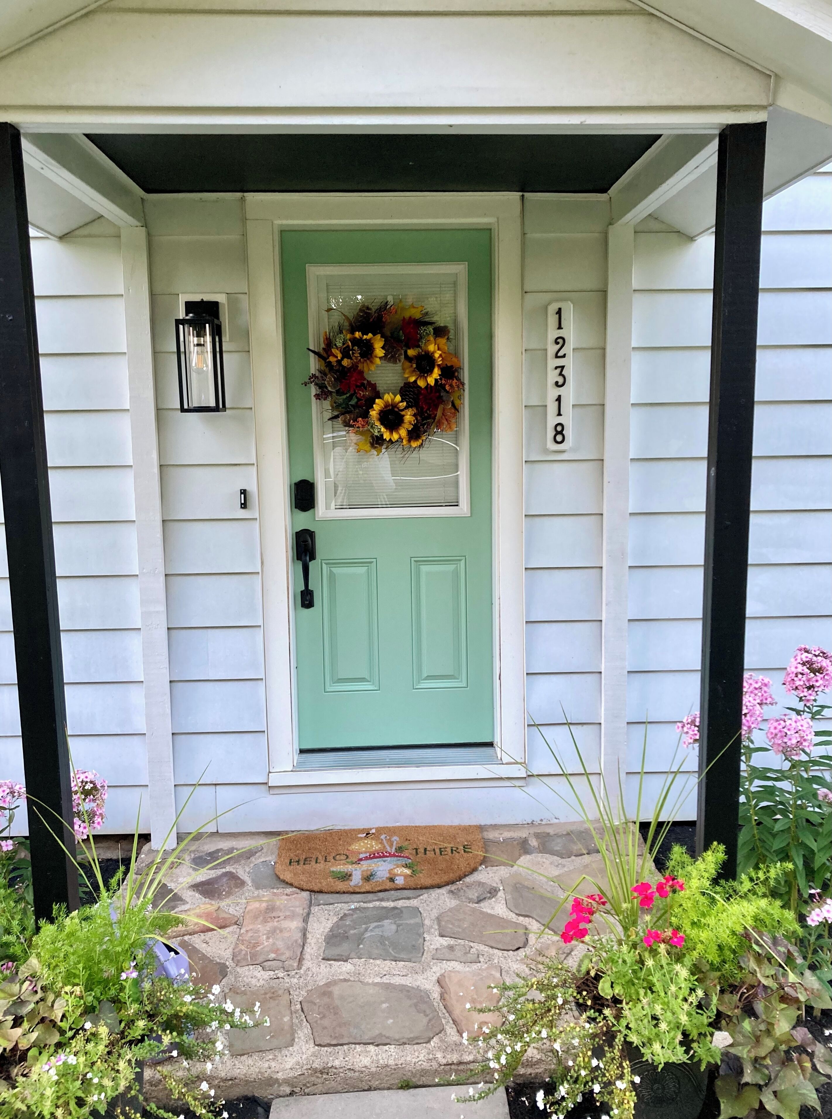 A front door with a green door, a wreath, and a mailbox.