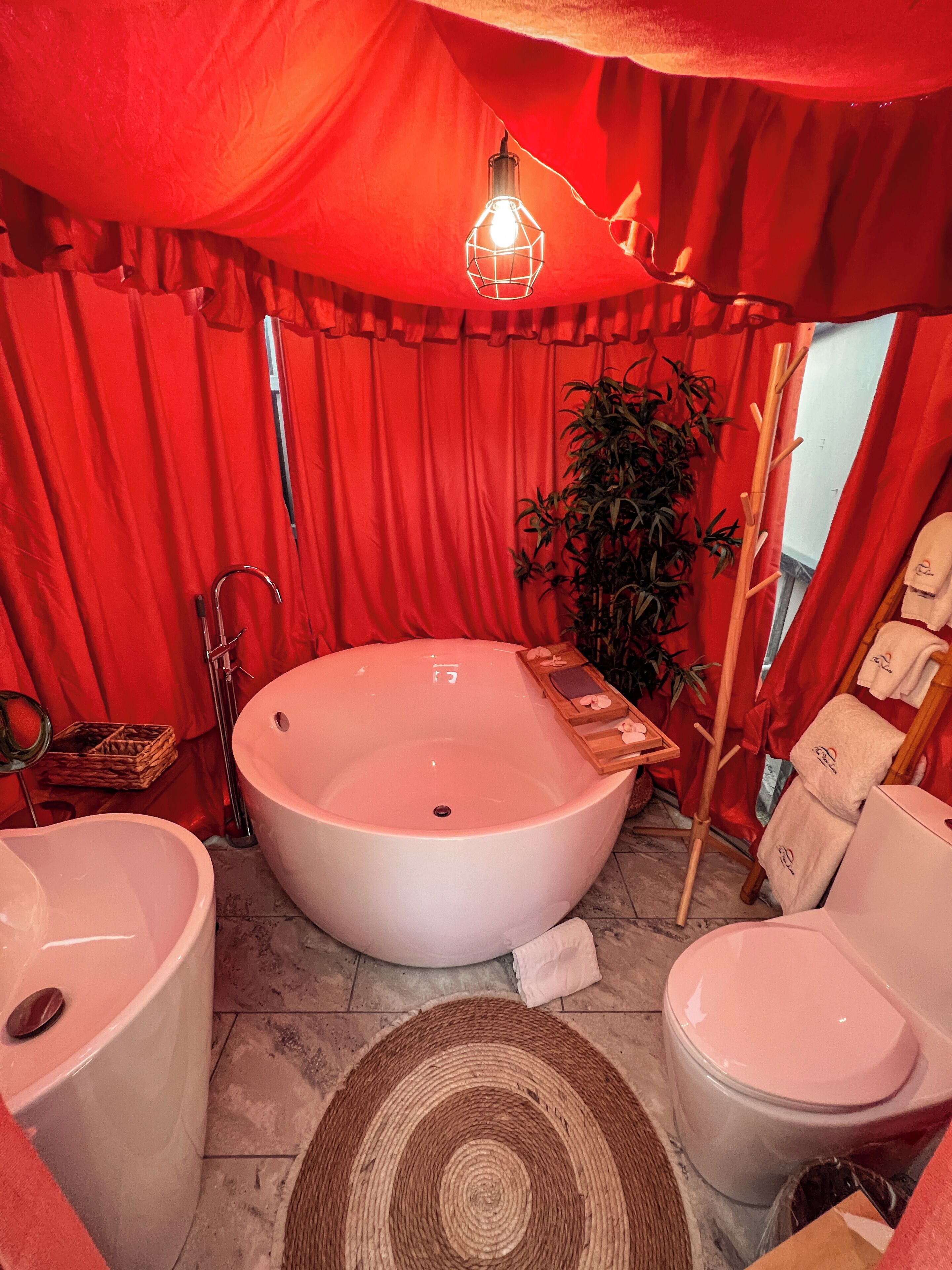 Un baño con una bañera grande, un lavamanos independiente, un inodoro, una silla para la ducha y un perchero para toallas.