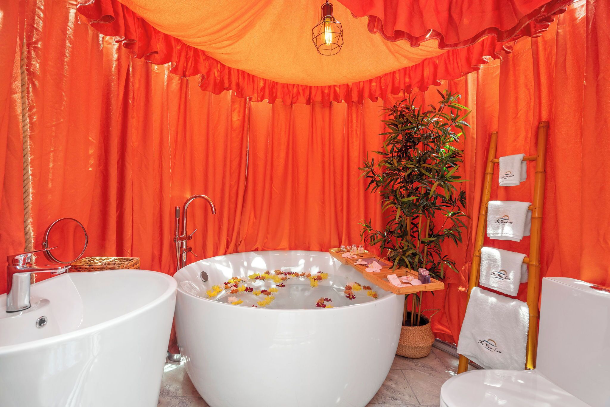 A bathroom with two sinks, a large bathtub, and a bamboo plant.