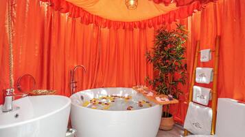A bathroom with two sinks, a large bathtub, and a bamboo plant.