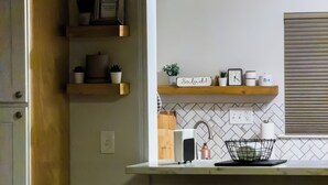 Cozinha moderna com forno embutido, pia e bancada com máquina de café.