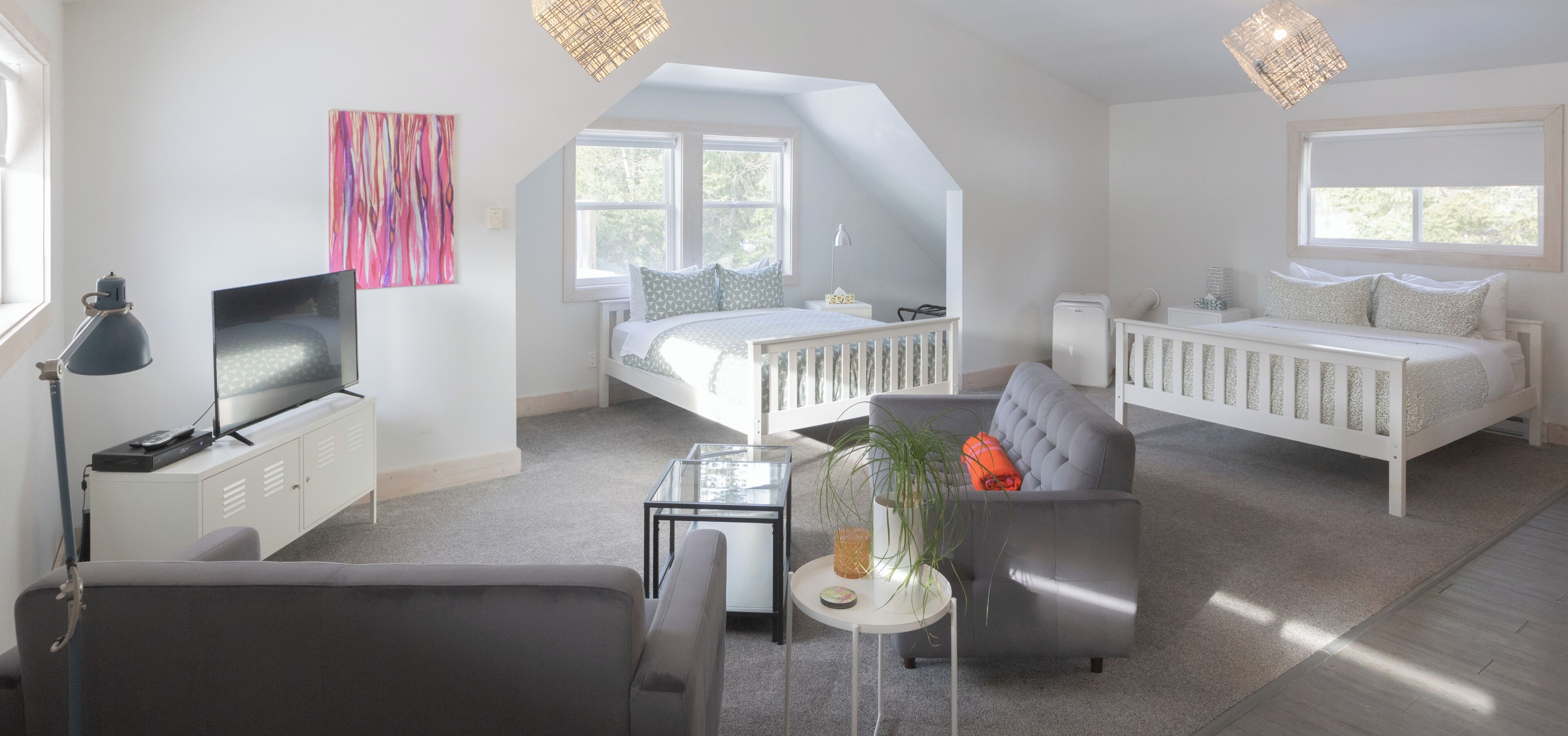 A modern bedroom with a loft bed, a sofa, a desk, and a television.