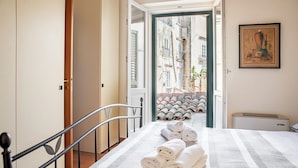 A hotel room with a bed, a view of the street outside, and a painting on the wall. - Duplex sul porto grande by Wonderful Italy (Syracuse)