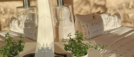 Una habitación moderna con un espejo curvo, plantas en macetas y una cama con ropa de cama estampada.