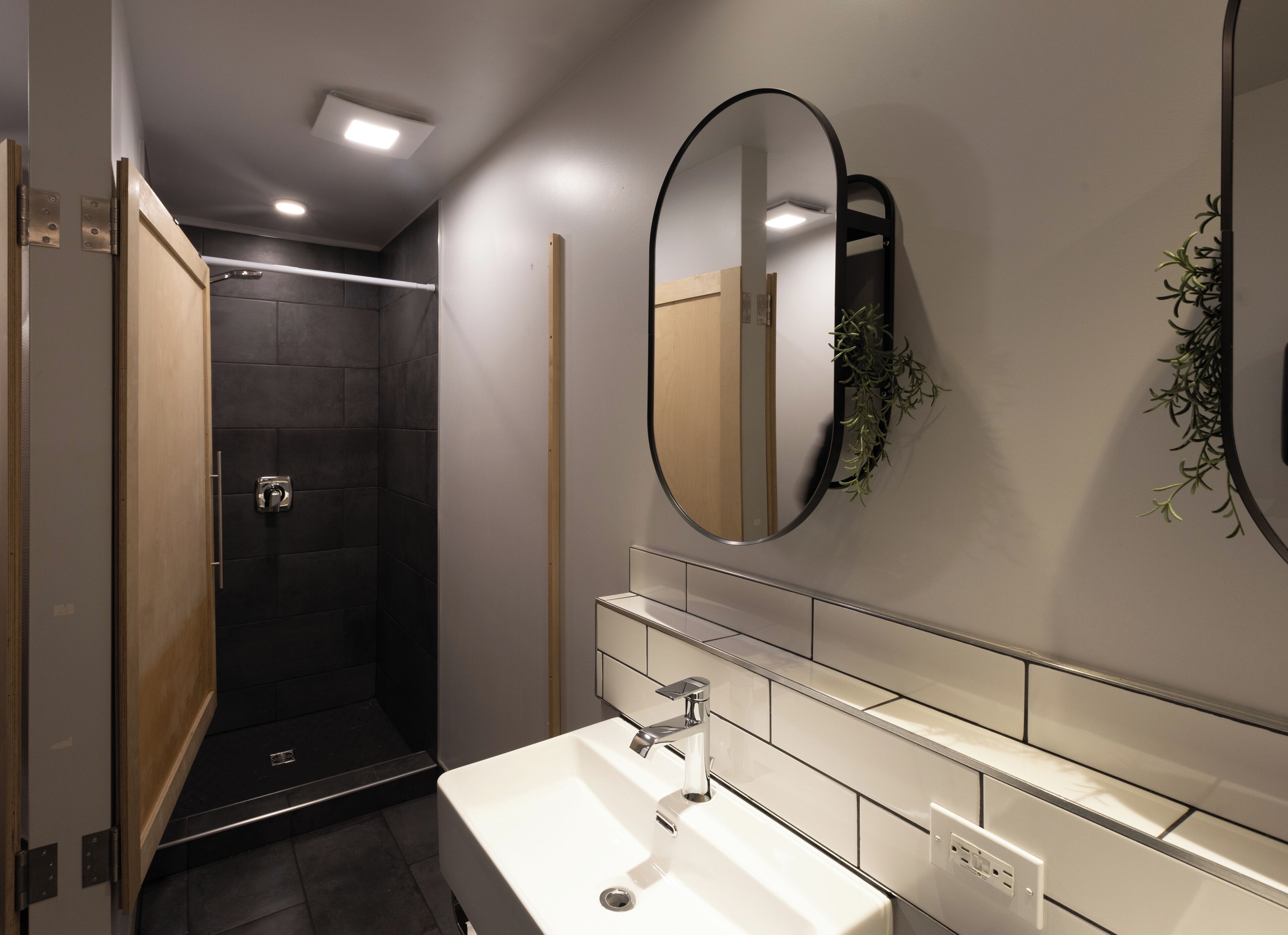Een moderne badkamer met een witte wastafel, een spiegel en een douchehoek.