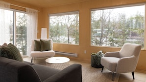 A modern living room with large windows, a sofa, a chair, and a coffee table. - River's Edge Retreat (Clearwater)