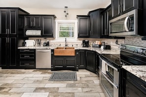 A modern kitchen with dark cabinetry, a built-in oven, a microwave, and a coffee station. - Modern Forest Escape w/ Pickleball, Hot Tub, Sauna, Gym, Fire Pit & Gameroom! (Mars Hill)