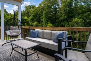 An outdoor deck with a sofa, a hanging chair, and a table.