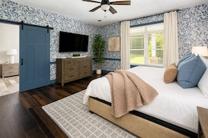 A bedroom with a bed, a TV, a dresser, and a plant. - Modern Forest Escape w/ Pickleball, Hot Tub, Sauna, Gym, Fire Pit & Gameroom! (Mars Hill)