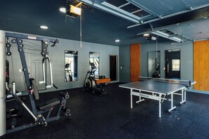 A gym with exercise equipment, a mirrored wall, and a ping pong table.