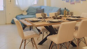 A dining area with a table set for four, a sofa, and a bed in the background. - D A Sea Breeze Next to the sea (Kalamata)