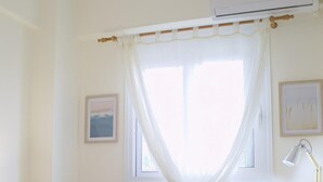 A hotel room with a bed, a desk, a chair, a lamp, and a window with sheer curtains. - D A Sea Breeze Next to the sea (Kalamata)