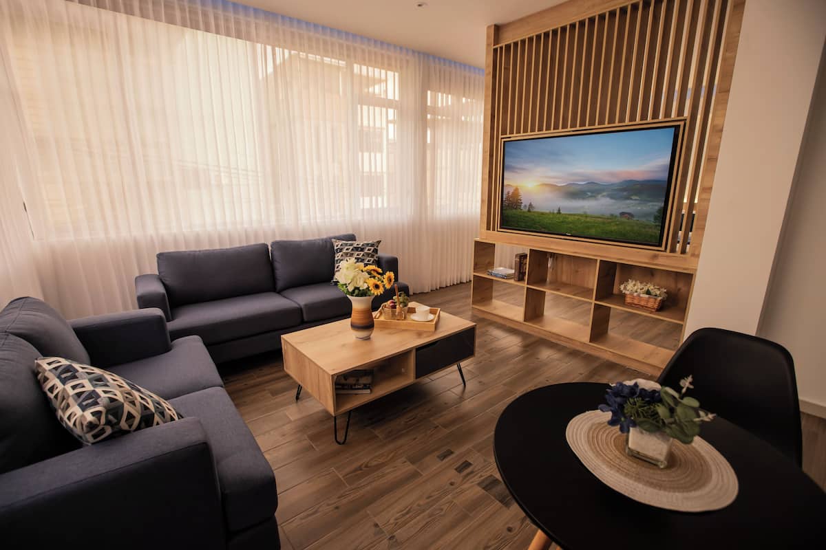 Ein modernes Wohnzimmer mit einer Couch, einem Couchtisch und einem an einer Holzwand montierten Fernseher.