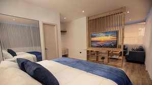 A modern hotel room with a large bed, a TV mounted on a wooden panel, a desk, and a seating area. - Harmonie (Guayaquil)