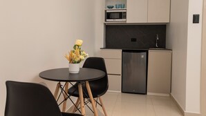 A compact kitchen with a dining area, including a table with chairs, a refrigerator, and a microwave. - Harmonie (Guayaquil)