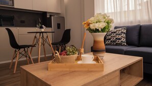 A modern living room with a wooden coffee table, a vase with flowers, and a dining area with chairs and a table. - Harmonie (Guayaquil)