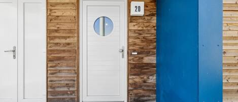 A building with two white doors, a blue wall, and a wooden panel design.