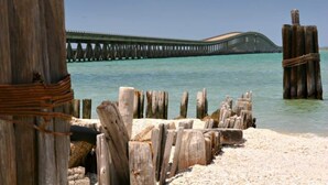 A wooden pier extending into a clear blue sea, with a sandy beach in the foreground. - Perfect Family Fun  | Pool, King Bed+BBQ+Sleeps 6 (Rockport)