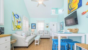 A cozy living room with a sofa, a coffee table, and a TV. There are blue chairs and a small table with a basket. - Perfect Family Fun  | Pool, King Bed+BBQ+Sleeps 6 (Rockport)