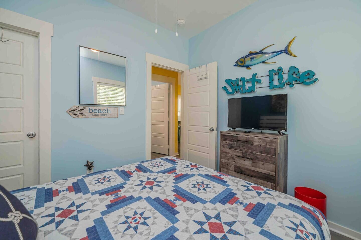 Une chambre à coucher comprenant un lit, une commode, un téléviseur et un élément décoratif mural.