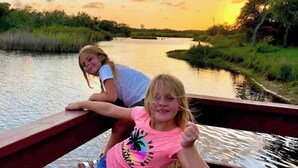 Twee personen op een houten brug over een rustige rivier tijdens zonsondergang.