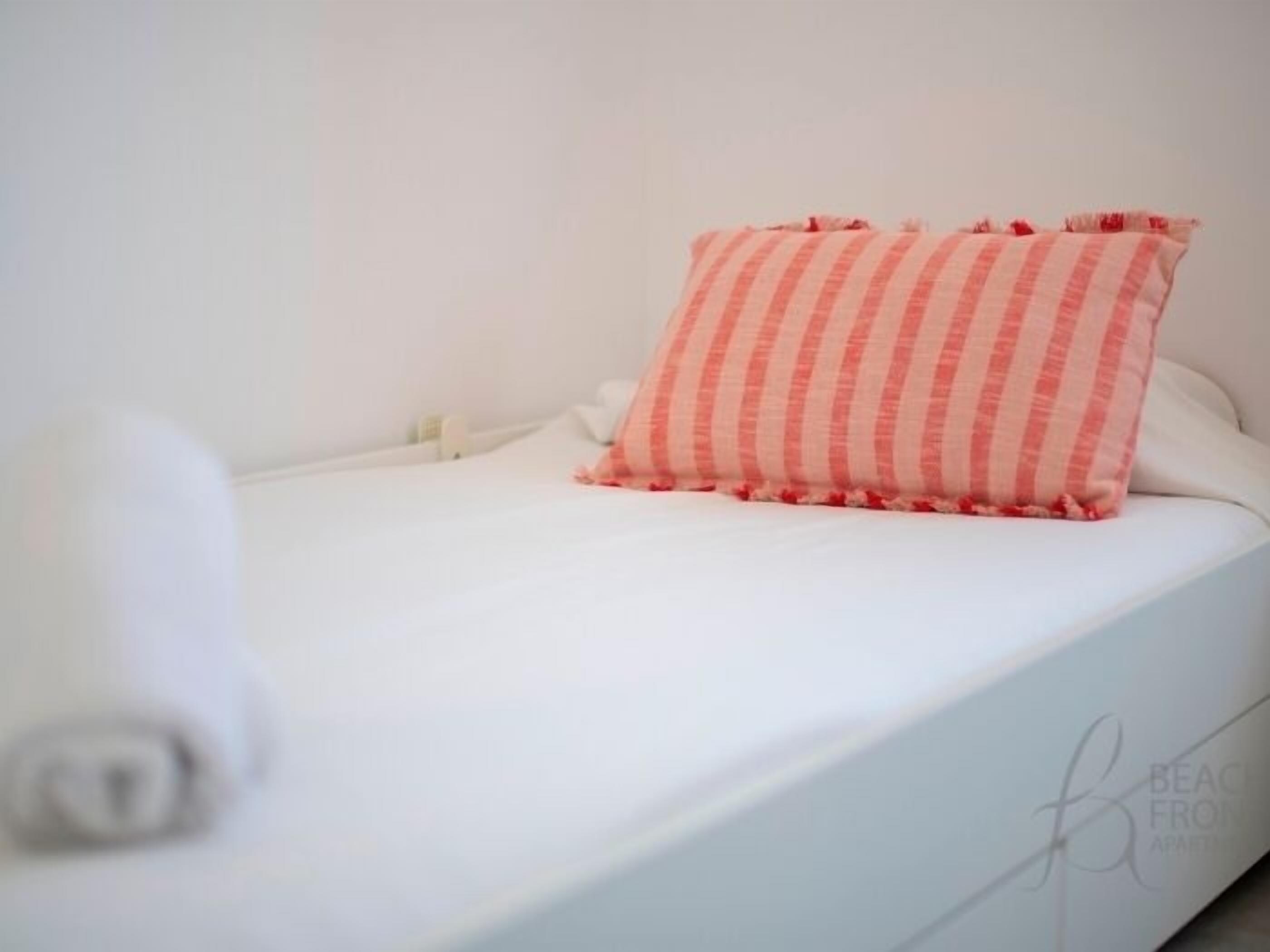 Un lit bien fait, avec un oreiller à rayures et une serviette blanche enroulée.