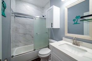 A modern bathroom with a glass-enclosed shower, a white toilet, a sink with a single faucet, and a cabinet above the sink. - Fisherman's Paradise Retreat - Tesla charger (Surfside Beach)