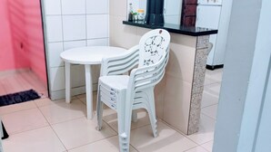 Eine kleine Küchenzeile mit weißer Arbeitsplatte, einem weißen Stuhl und einem weißen Tisch.