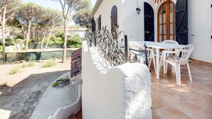 Un patio con una mesa y sillas blancas, un muro de piedra y una valla metálica.