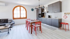 Una cocina moderna con armarios grises, una mesa de comedor con sillas rojas y un ventanal grande.
