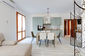 Una sala de estar moderna con un sofá, una mesa de comedor con sillas y una cocina con armarios y electrodomésticos.