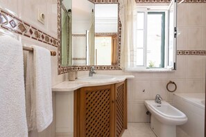 Ein Badezimmer mit Waschbecken, Spiegel, Fenster und Bidet.