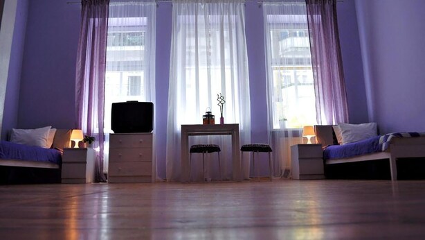 Una habitació amb dos llits, un escriptori i una finestra amb cortines.