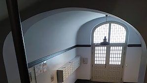 Un passadís amb un paviment de rajoles, una banca i una porta amb finestreta.