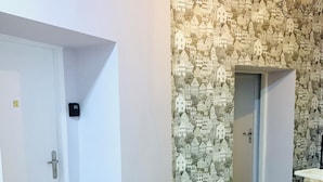 Una habitació amb terra de fusta, una porta blanca i una paret amb un disseny imprès de cases.
