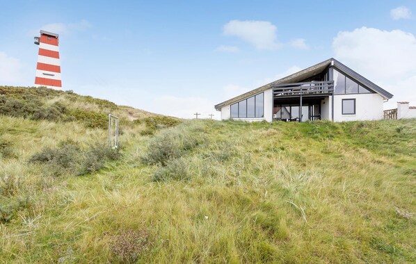 Een modern huis met een schuin dak, grote ramen en een plat dakuitbouw.
