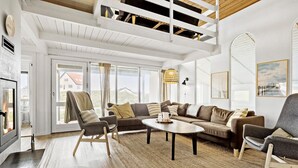 A spacious living room with a high ceiling, a fireplace, a sofa set, and a dining table. - Awesome home in Thisted with sauna (Thisted)